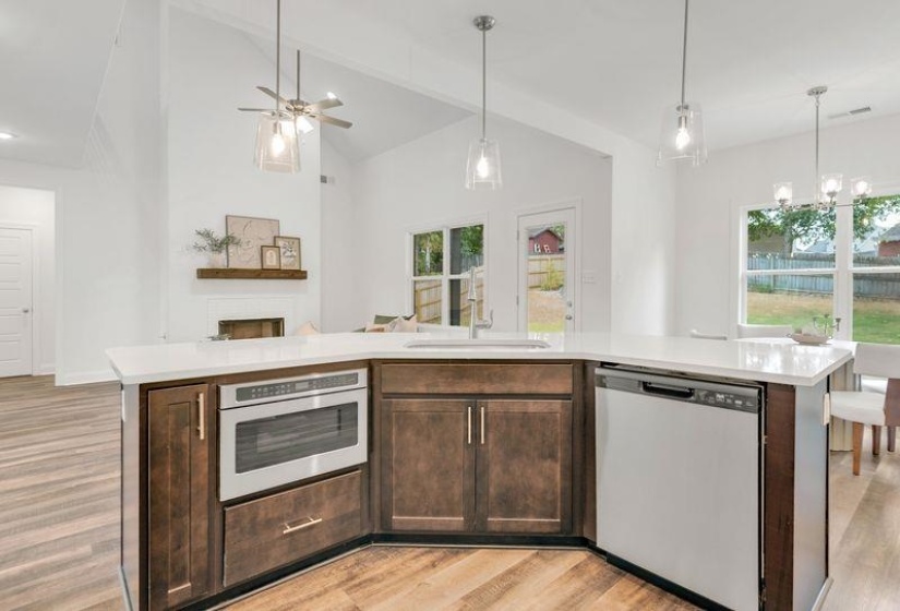 Kitchen with a center island with sink, dark brown cabinetry, open floor plan, stainless steel appliances, and light wood finished floors