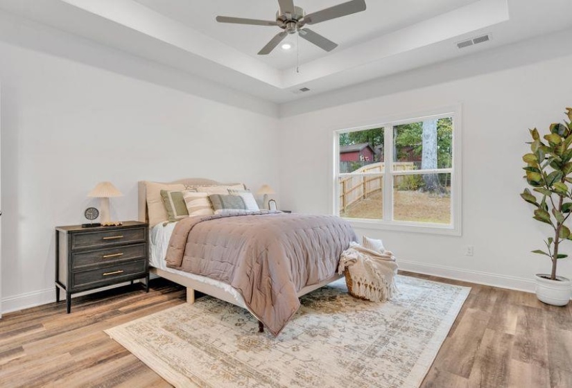 Bedroom featuring a raised ceiling, light wood finished floors, ceiling fan, and recessed lighting