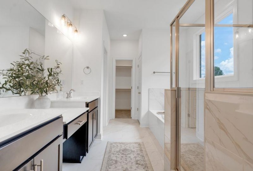 Bathroom with a garden tub, a stall shower, double vanity, a spacious closet, and light tile patterned flooring