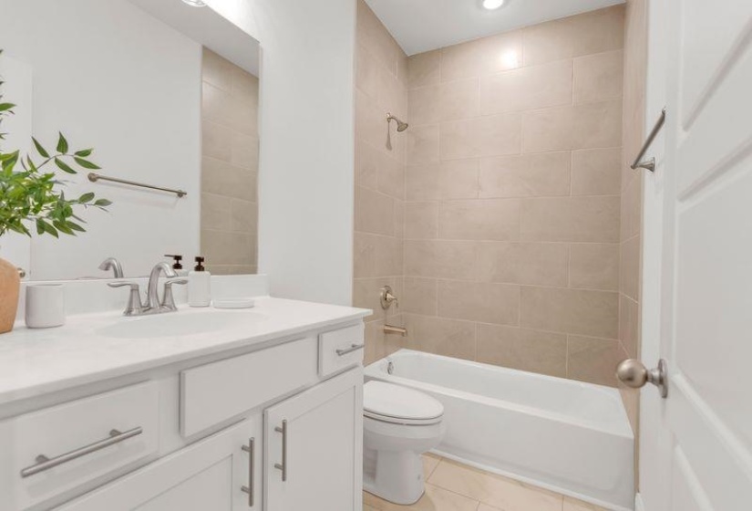Bathroom with washtub / shower combination, vanity, light tile patterned flooring, and recessed lighting