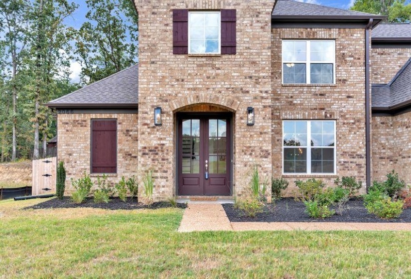 View of front of home with brick siding, a front yard, french doors, and roof with shingles