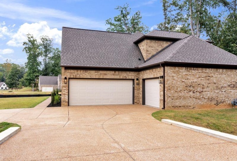 View of front of property featuring a shingled roof, brick siding, driveway, a front yard, and an attached garage