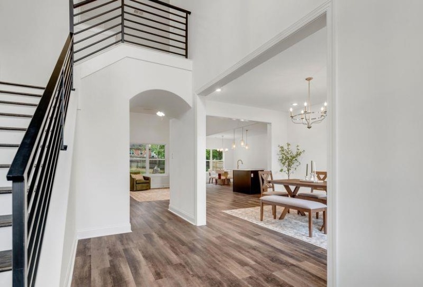 Entrance foyer featuring stairway, dark wood-type flooring, a high ceiling, arched walkways, and a chandelier