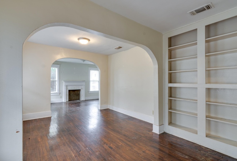 Unfurnished room featuring built in shelves, dark wood finished floors, and a fireplace