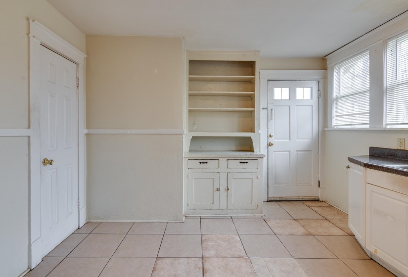 Kitchen featuring white cabinets, light tile patterned floors, dark countertops, and open shelves