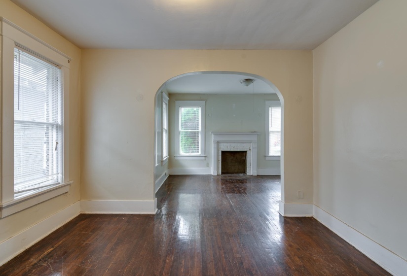 Unfurnished living room with arched walkways, a fireplace, and dark wood finished floors