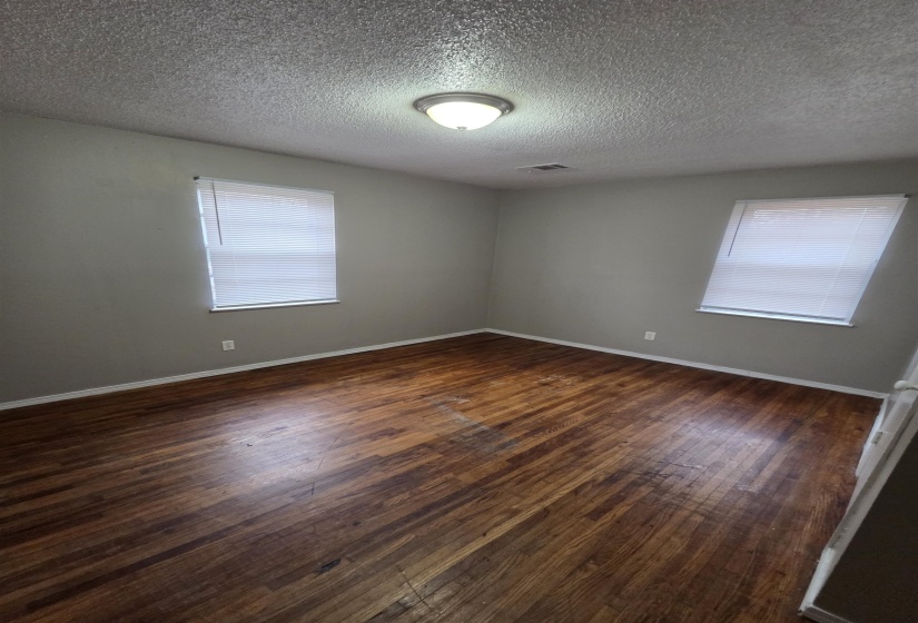 Empty room featuring dark wood-style flooring and a textured ceiling