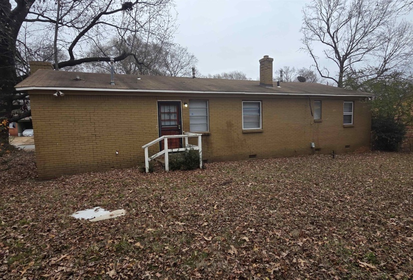 Back of house with crawl space, a chimney, and brick siding