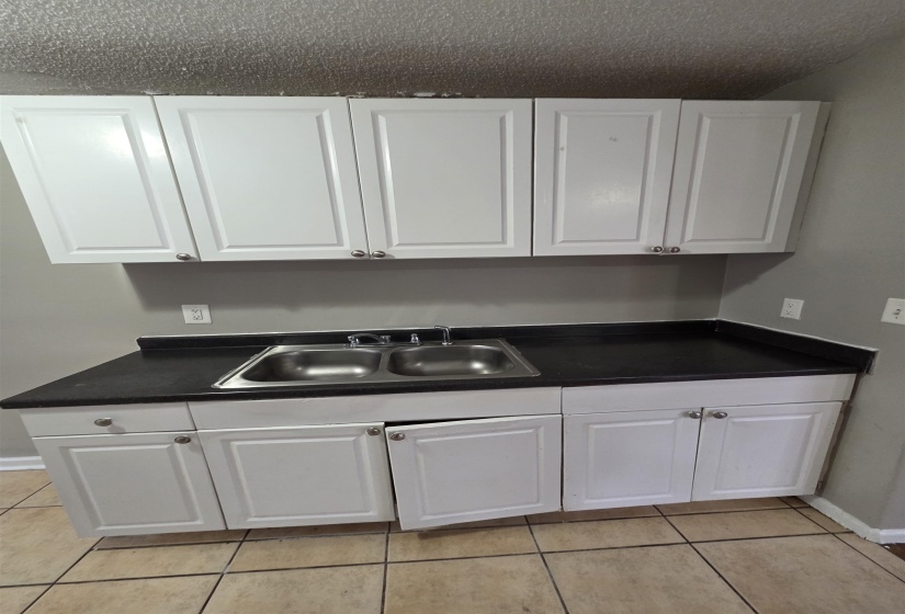 Kitchen featuring white cabinetry, dark countertops, and light tile patterned flooring