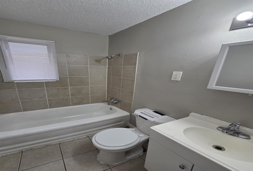 Bathroom featuring vanity, light tile patterned floors, shower / tub combination, and a textured ceiling