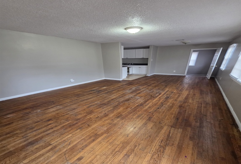 Unfurnished living room with dark wood-type flooring and a textured ceiling