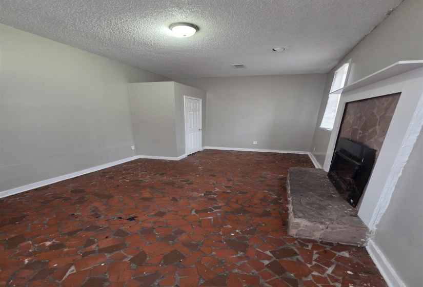 Unfurnished living room featuring a fireplace with raised hearth and a textured ceiling