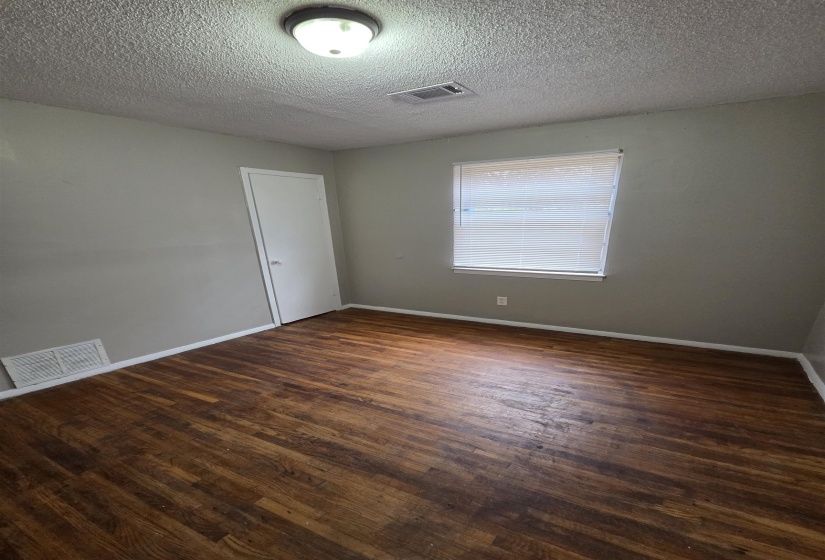 Unfurnished room featuring dark wood-style flooring and a textured ceiling