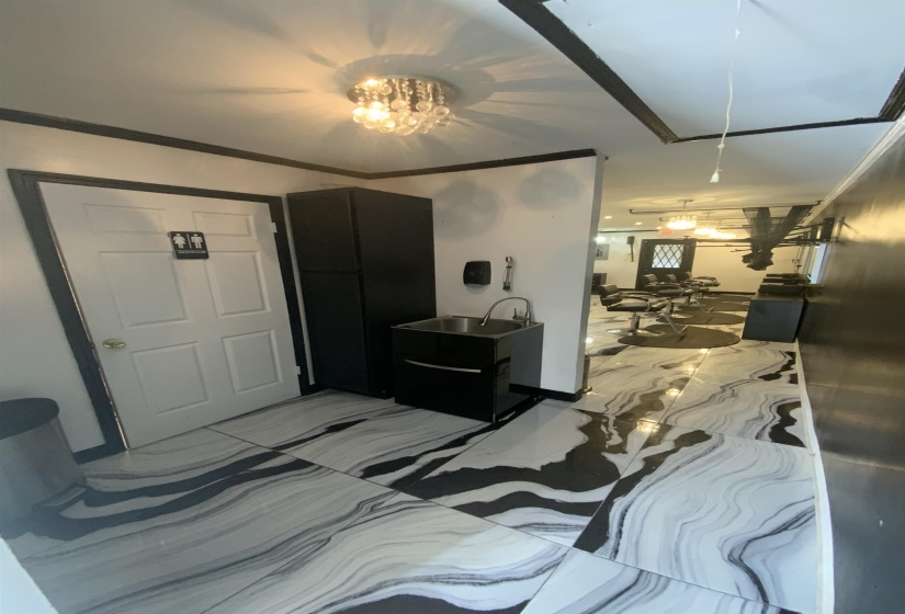 Bedroom with crown molding, attic access, and light marble finish floors
