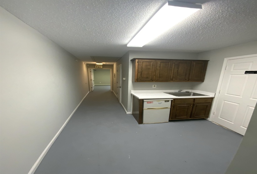 Kitchen featuring concrete floors, light countertops, dark brown cabinetry, and a textured ceiling