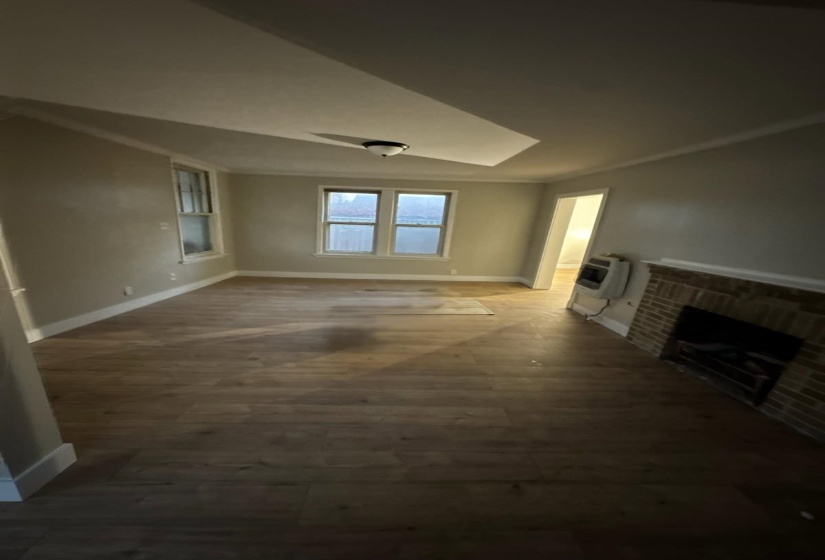 Unfurnished living room with a brick fireplace, heating unit, and dark wood-style floors