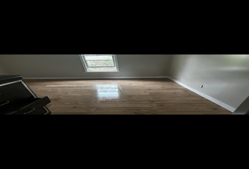 Additional living space with light wood-style floors and vaulted ceiling