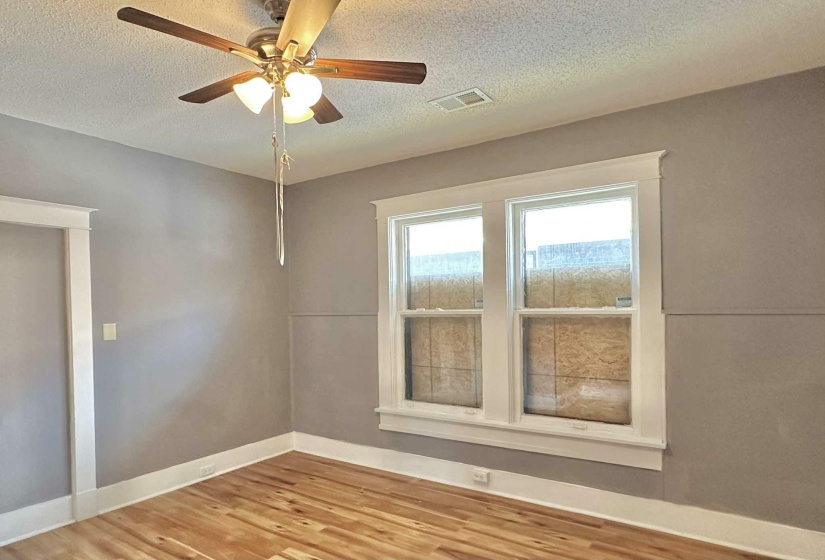 Unfurnished room with a textured ceiling, wood finished floors, and a ceiling fan