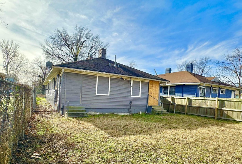 Rear view of house with a fenced backyard, a chimney, and entry steps