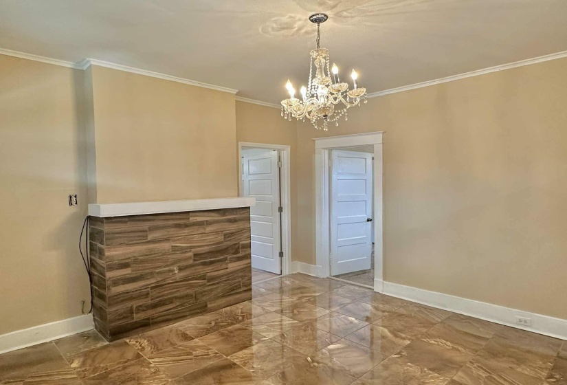 Unfurnished dining area with marble finish flooring, crown molding, and a chandelier