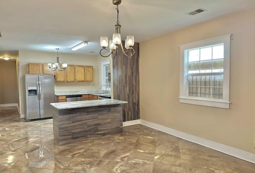 Kitchen featuring a chandelier, appliances with stainless steel finishes, hanging light fixtures, a peninsula, and light marble finish floors
