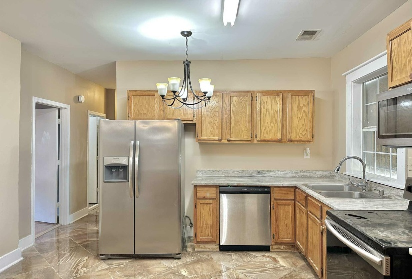 Kitchen with stainless steel appliances, light countertops, decorative light fixtures, a chandelier, and light marble finish flooring