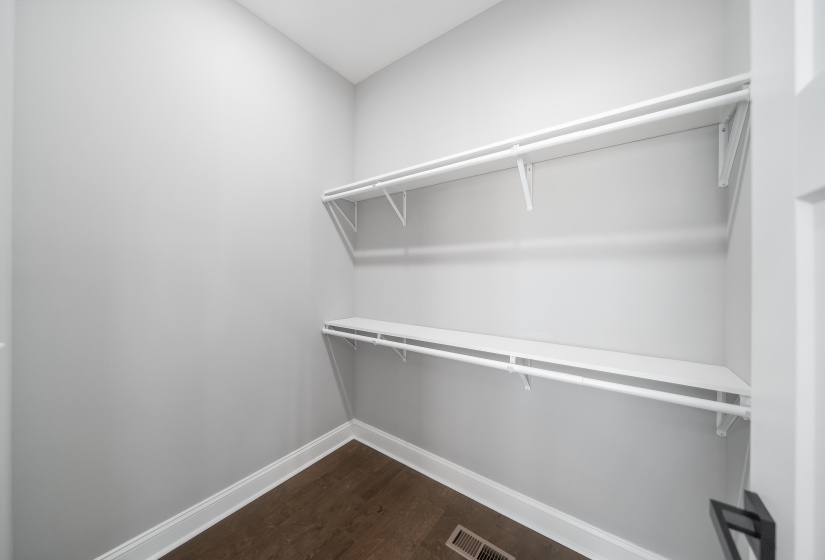 Walk in closet with dark wood-type flooring
