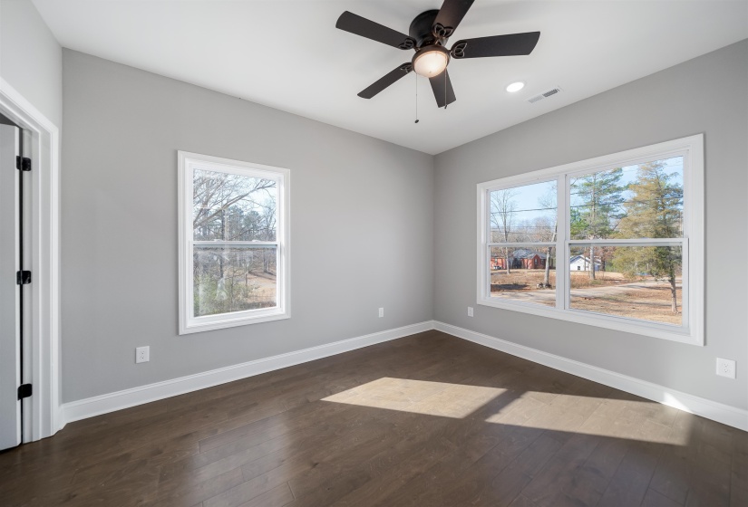 Unfurnished room featuring dark wood-type flooring, plenty of natural light, and ceiling fan