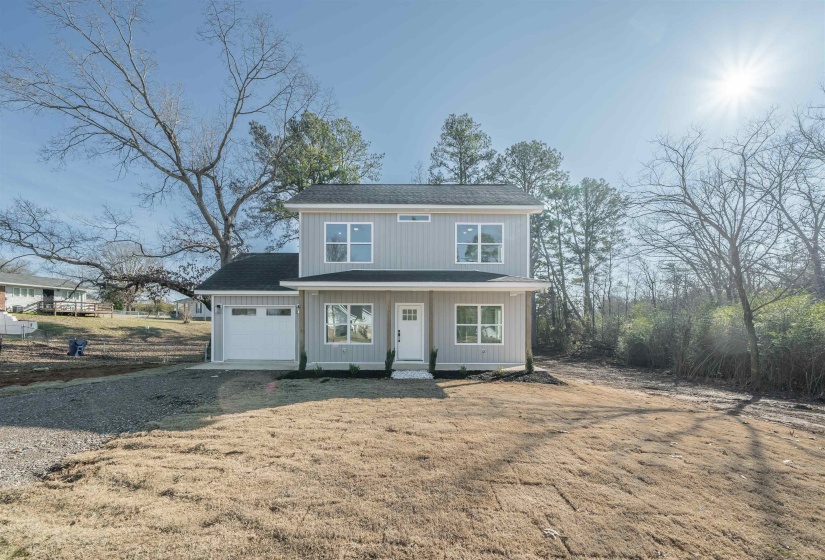 Traditional-style home featuring covered porch, driveway, roof with shingles, and a front yard
