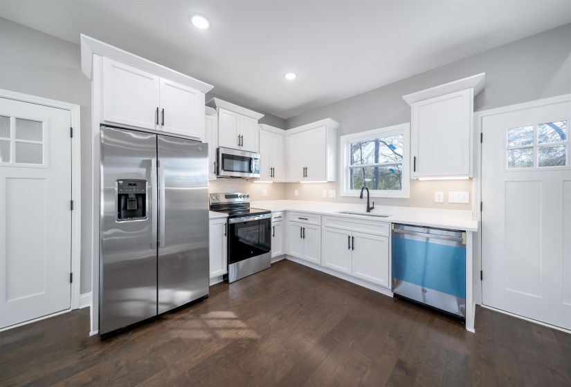 Kitchen featuring appliances with stainless steel finishes, white cabinetry, dark wood-style flooring, recessed lighting, and light stone countertops