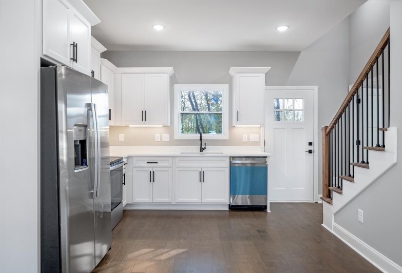 Kitchen with appliances with stainless steel finishes, white cabinets, dark wood-type flooring, recessed lighting, and light stone counters
