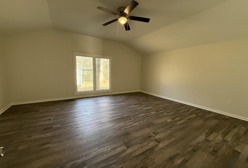 Master bedroom featuring vaulted ceiling, dark wood-type flooring, and ceiling fan