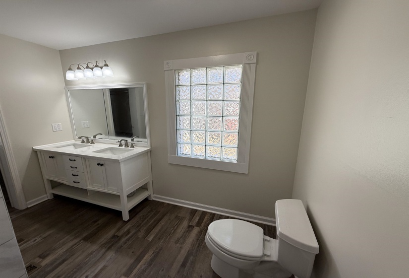 Bathroom with double vanity and dark wood-type flooring