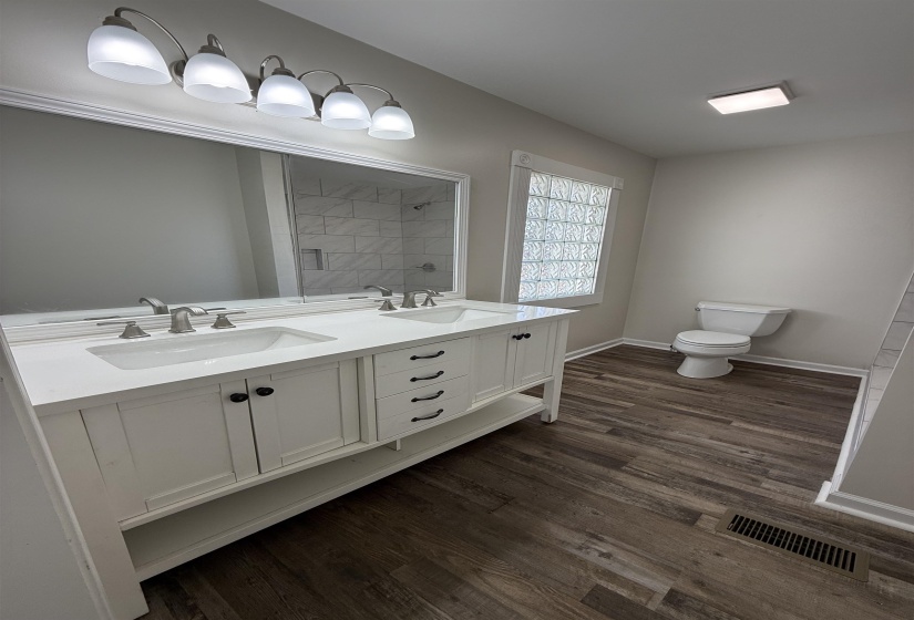 Bathroom with double vanity and dark wood-style flooring