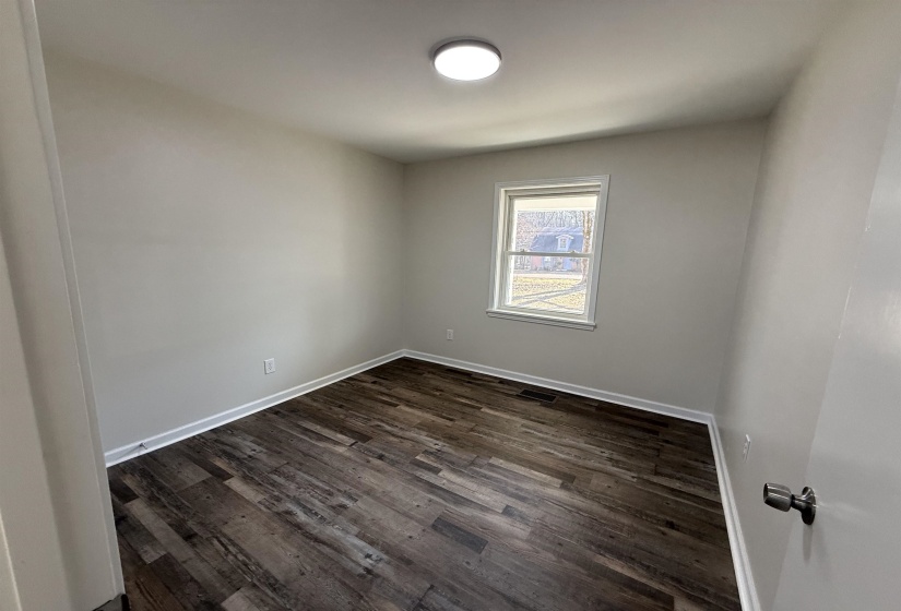 Guest room featuring dark wood-style flooring and baseboards