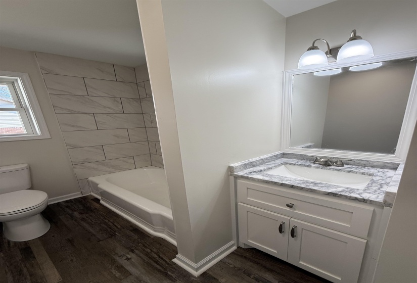Bathroom with vanity, dark wood-style floors, and shower / washtub combination