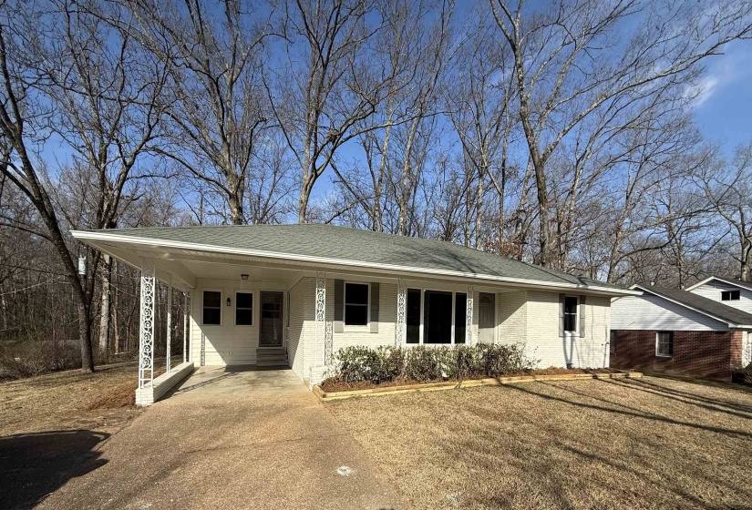 Single story home featuring a porch, a carport, concrete driveway, roof with shingles, and brick siding
