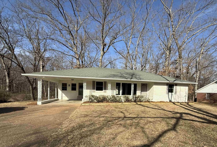 Ranch-style house featuring a porch, a carport, driveway, and a front lawn