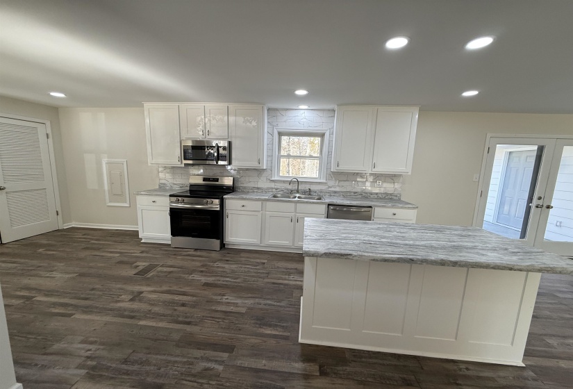 Kitchen with white cabinetry, appliances with stainless steel finishes, decorative backsplash, recessed lighting, and dark wood-type flooring