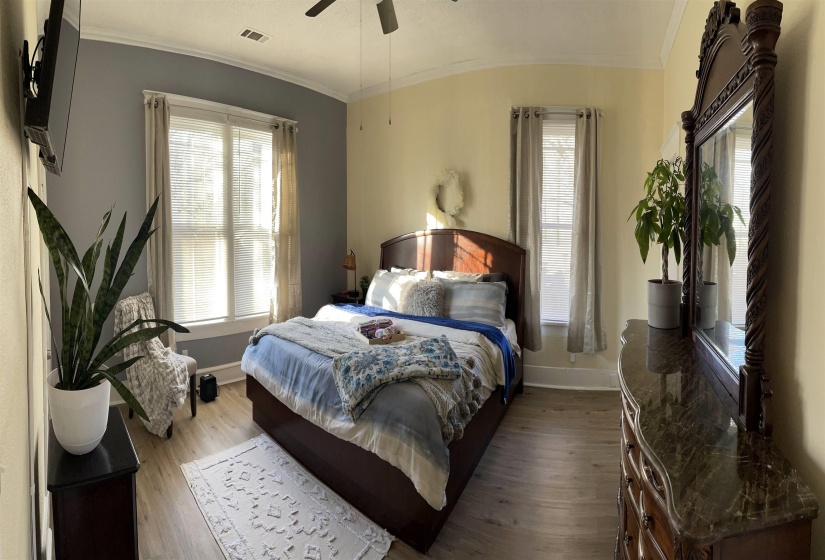 Spacious bedroom featuring wood-finish flooring, crown molding, and a ceiling fan