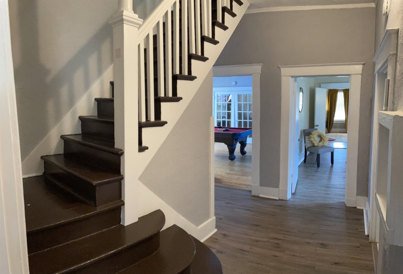 Main level foyer with wood-finish flooring and a staircase featuring dark wood treads and white risers