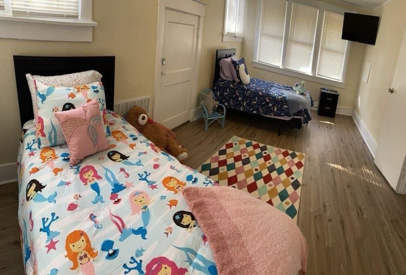 Spacious room featuring wood-finish flooring, light-toned walls, and multiple windows with blinds
