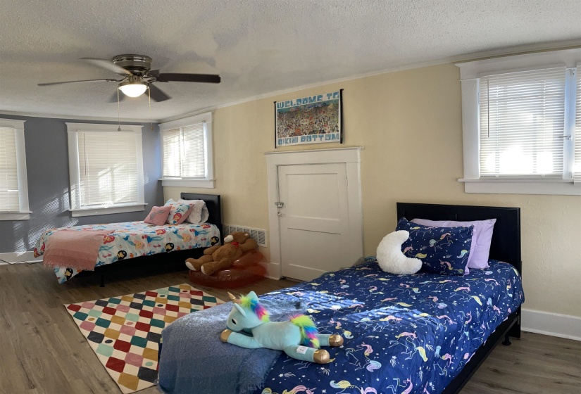 Spacious room featuring wood-finish flooring and multiple windows with blinds