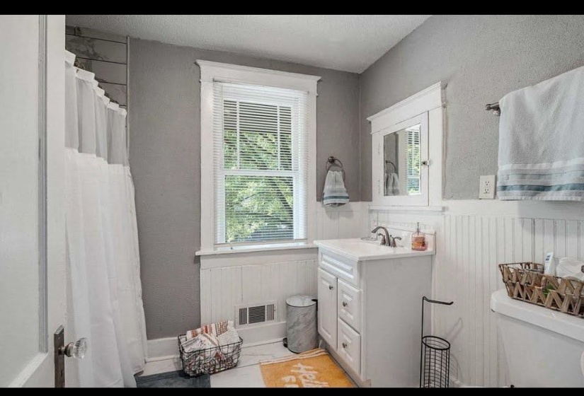 Bathroom featuring a white vanity with integrated sink, white beadboard wainscoting, and a built-in medicine cabinet