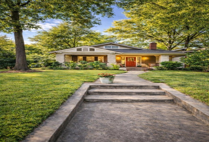 Craftsman-style home featuring a prominent red front door, covered porch, and a brick chimney