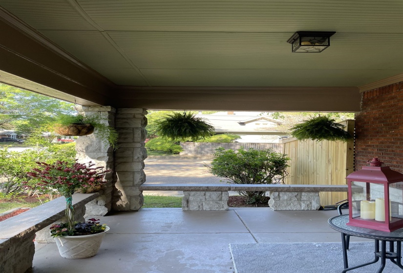 Inviting covered porch featuring a beadboard ceiling, recessed lighting, brick siding, and stone pillar accents