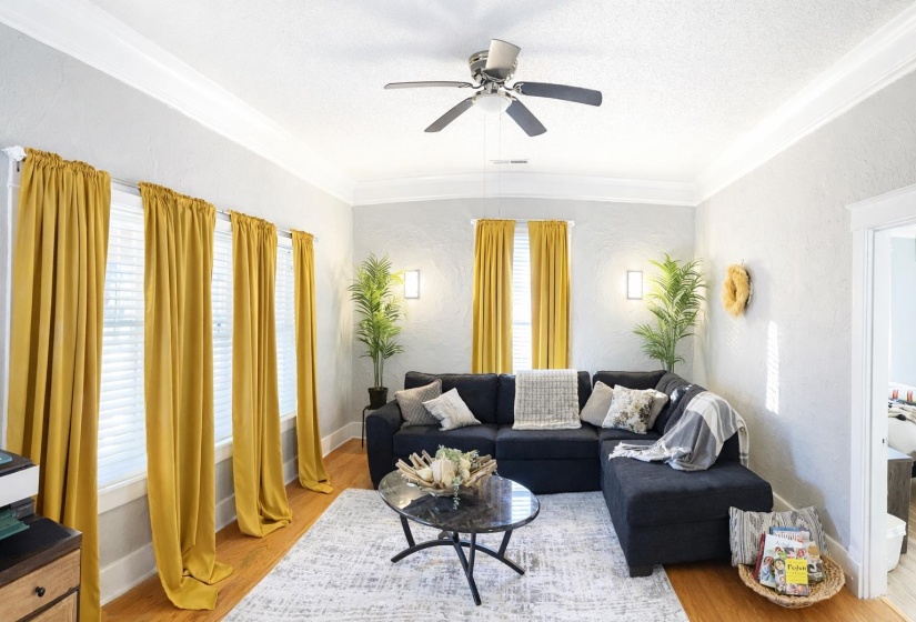 Living area featuring multiple windows with blinds, crown molding, and wood-finish flooring