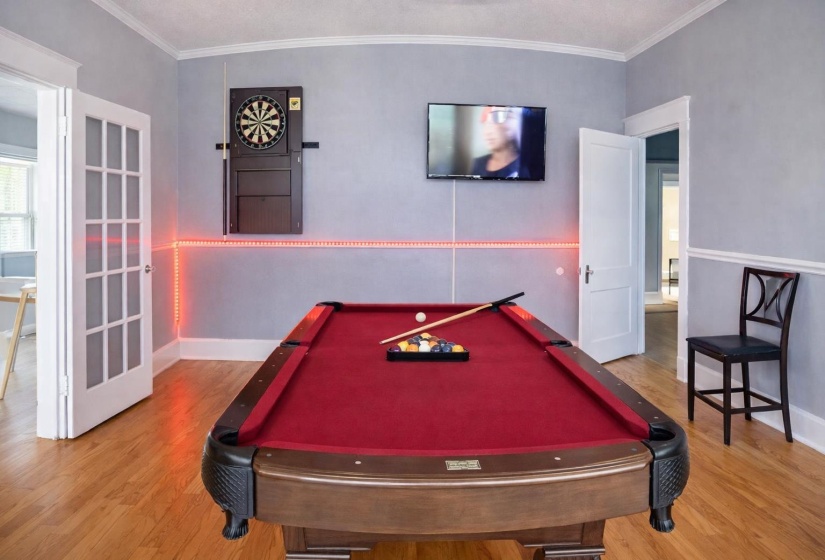 Recreation room featuring wood-finish flooring, light gray walls with chair rail molding, and white crown molding