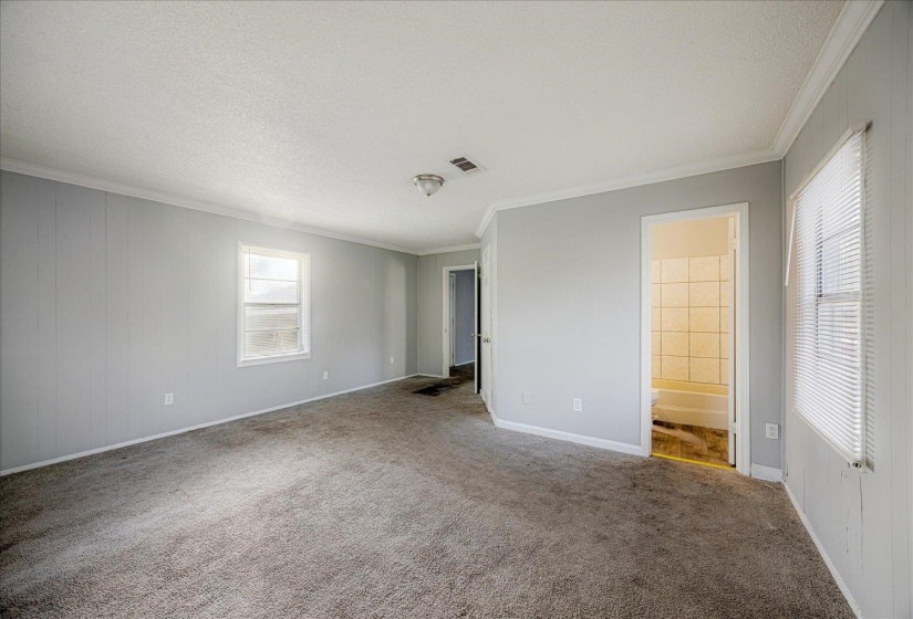 Unfurnished bedroom featuring crown molding, carpet, a textured ceiling, and ensuite bathroom