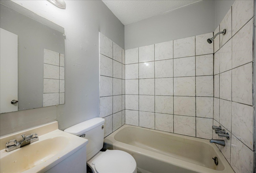 Full bath with washtub / shower combination, a textured ceiling, and vanity
